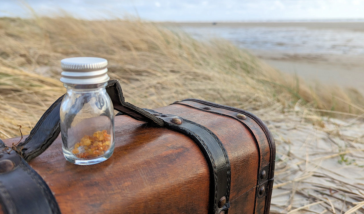 Holzkiste mit einem kleinen Glas Bernstein Krümeln am Strand von Fanø Dänemark