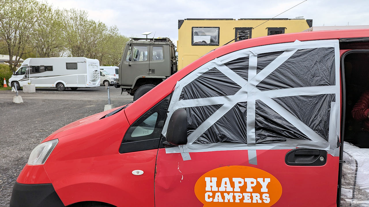 Happy Camper Auto mit provisorisch abgedichteter Fensterscheibe. 