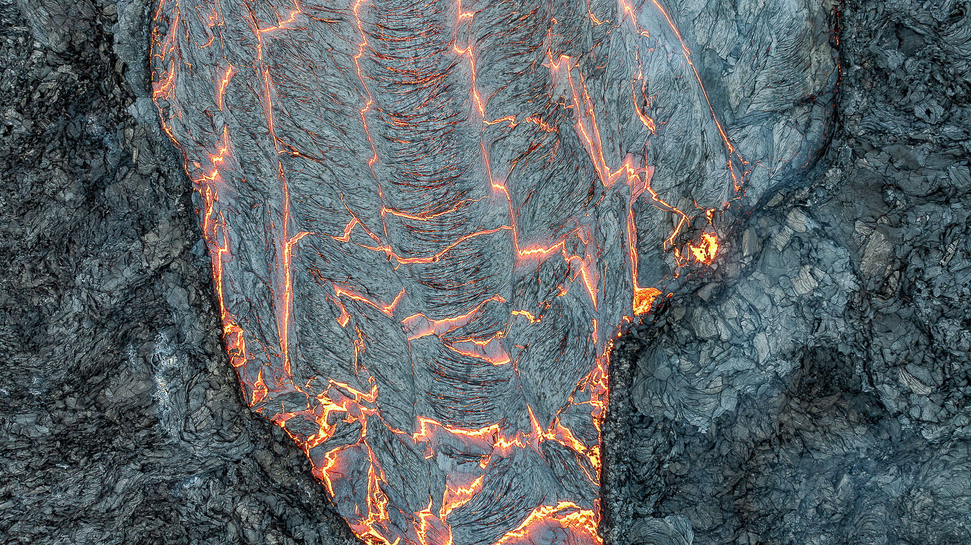 Detailaufnahme glühende Lava mit schuppig schwarzer Haut aus erkalteter Lava Island