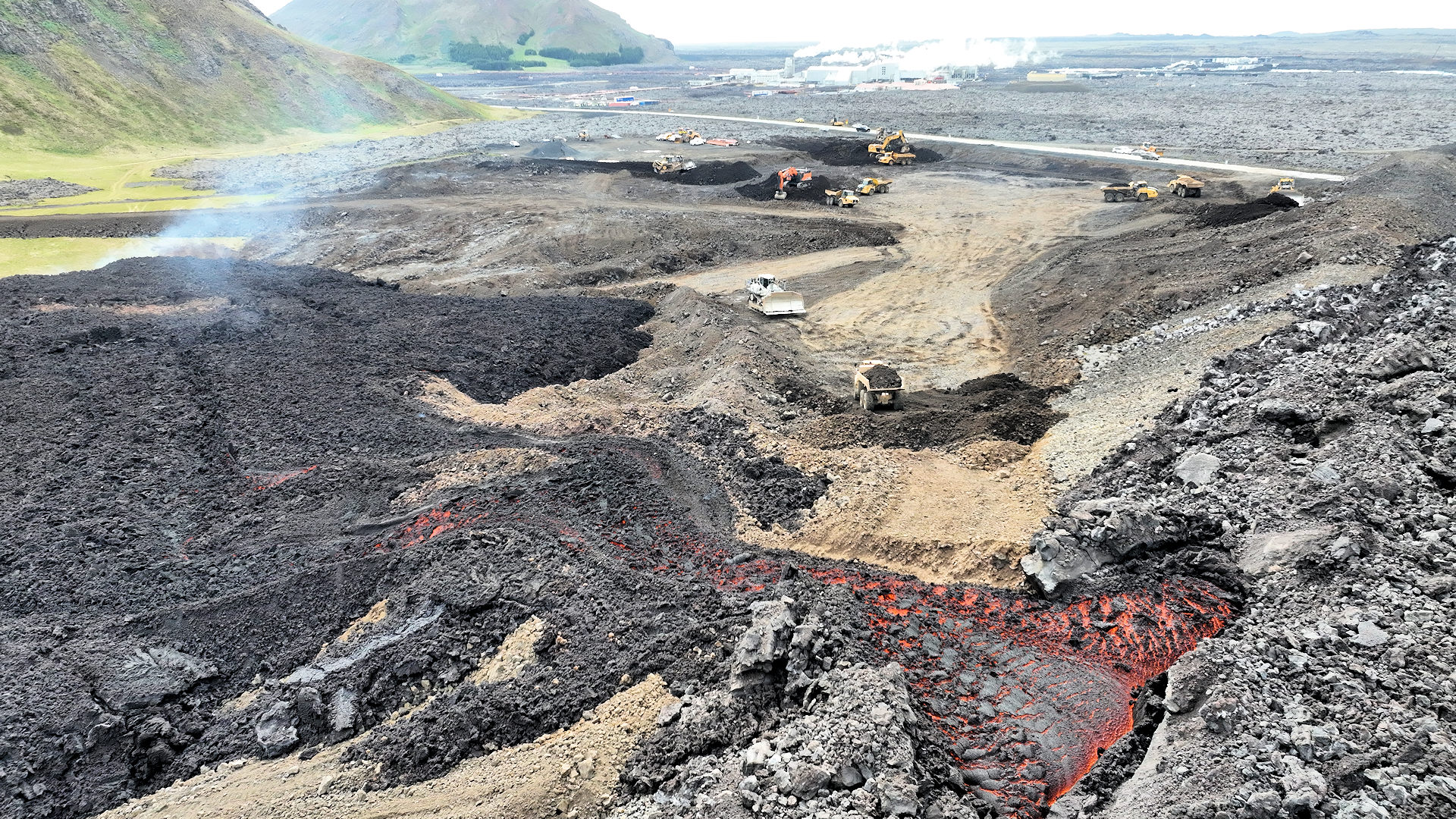 Bauarbeitern am Svartsengi Schutzwall in Island. Mehrere Baufahrzeuge verstärken eine Barriere gegen glühende Lava