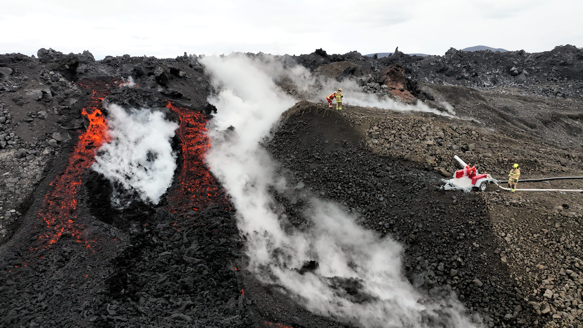 Feuerwehrleute beim Vulkan Schutzwall in Island neben glühender Lava 