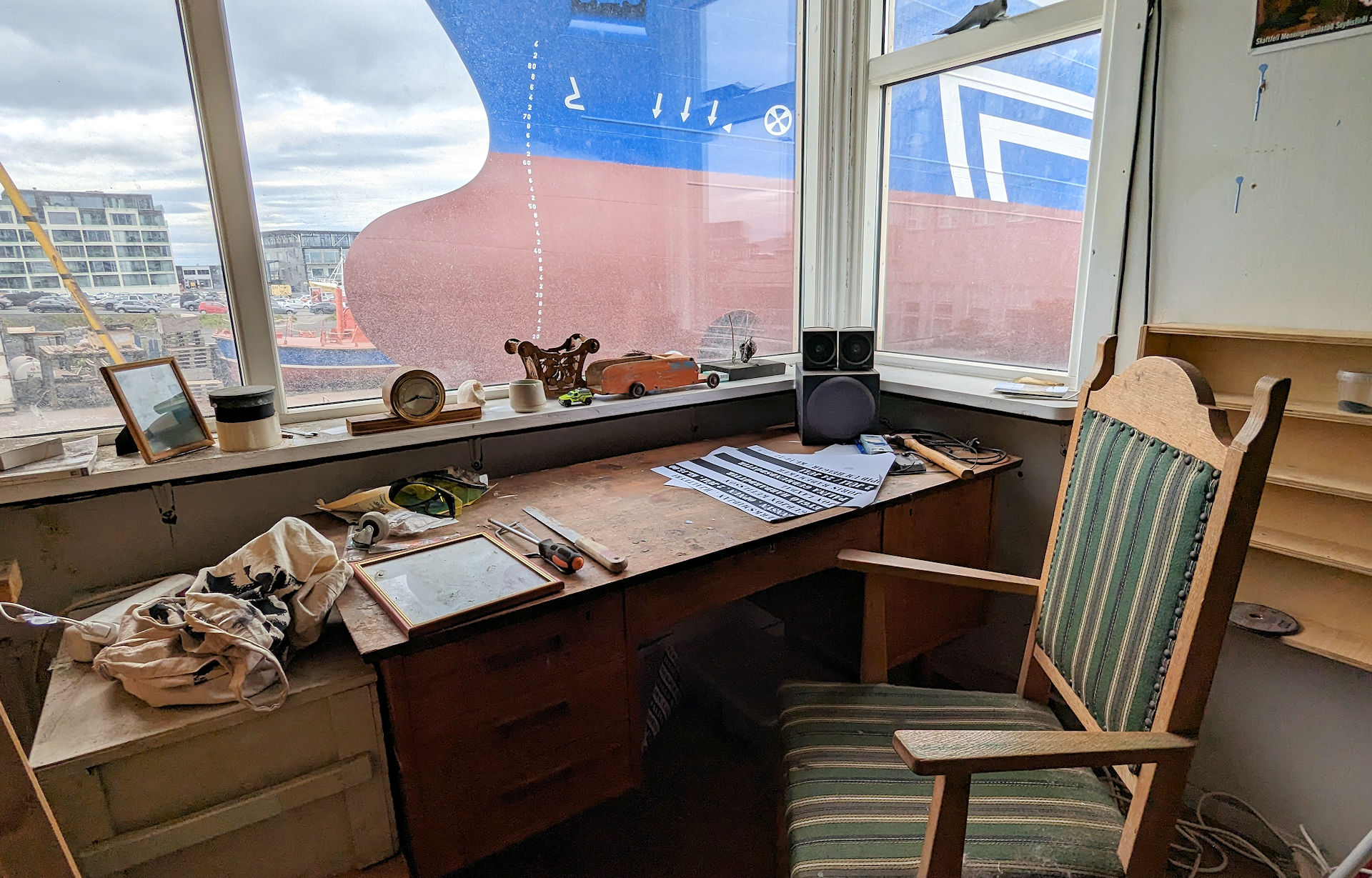 Schreibtisch und Stuhl in einem Büro mit Blick auf ein Schiff im Fenster