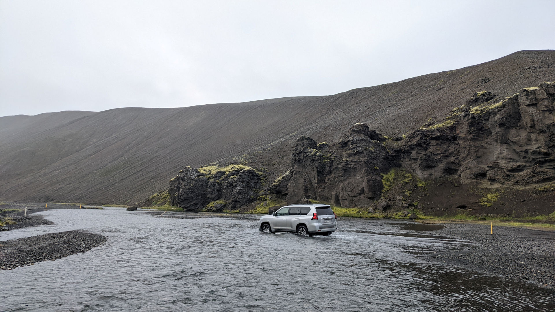 Ein Auto fährt in Island durch eine breite, aber sehr flache und ungefährliche Furt oder Wasserstelle