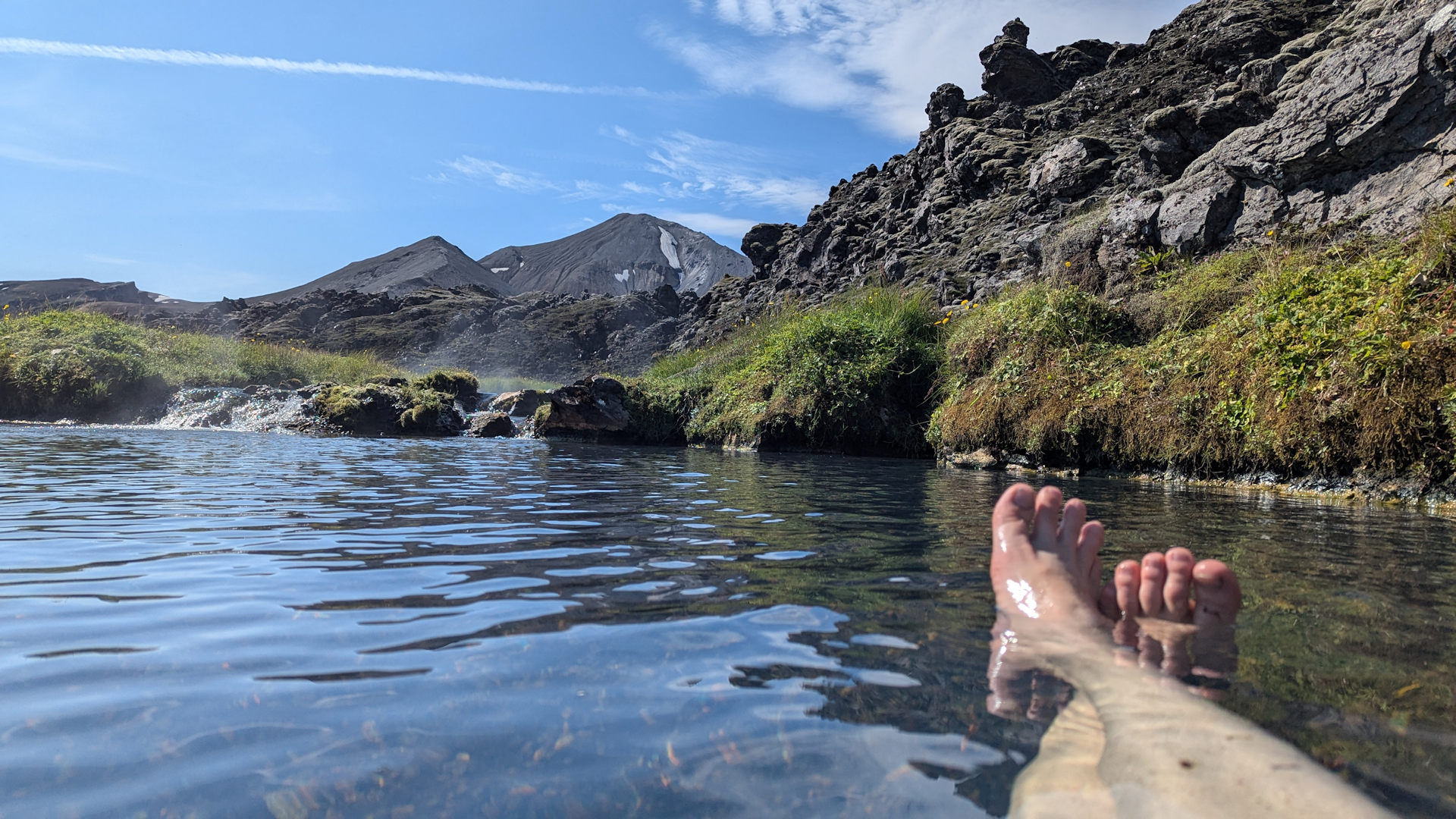 Bad in der Hochland Quelle Landmannalaugar. Zwei nackte Beine sind im warmen Wasser zu sehen