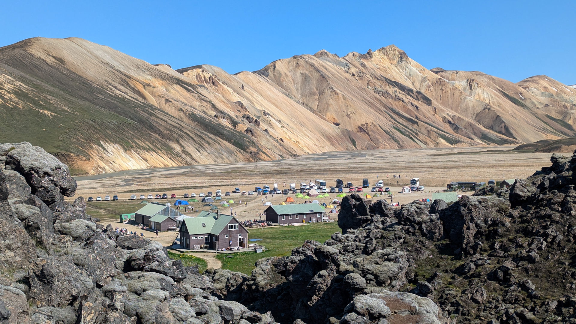 Campingplatz Landmannalaugar mit Zelten vor gelben Bergen im Hintergrund