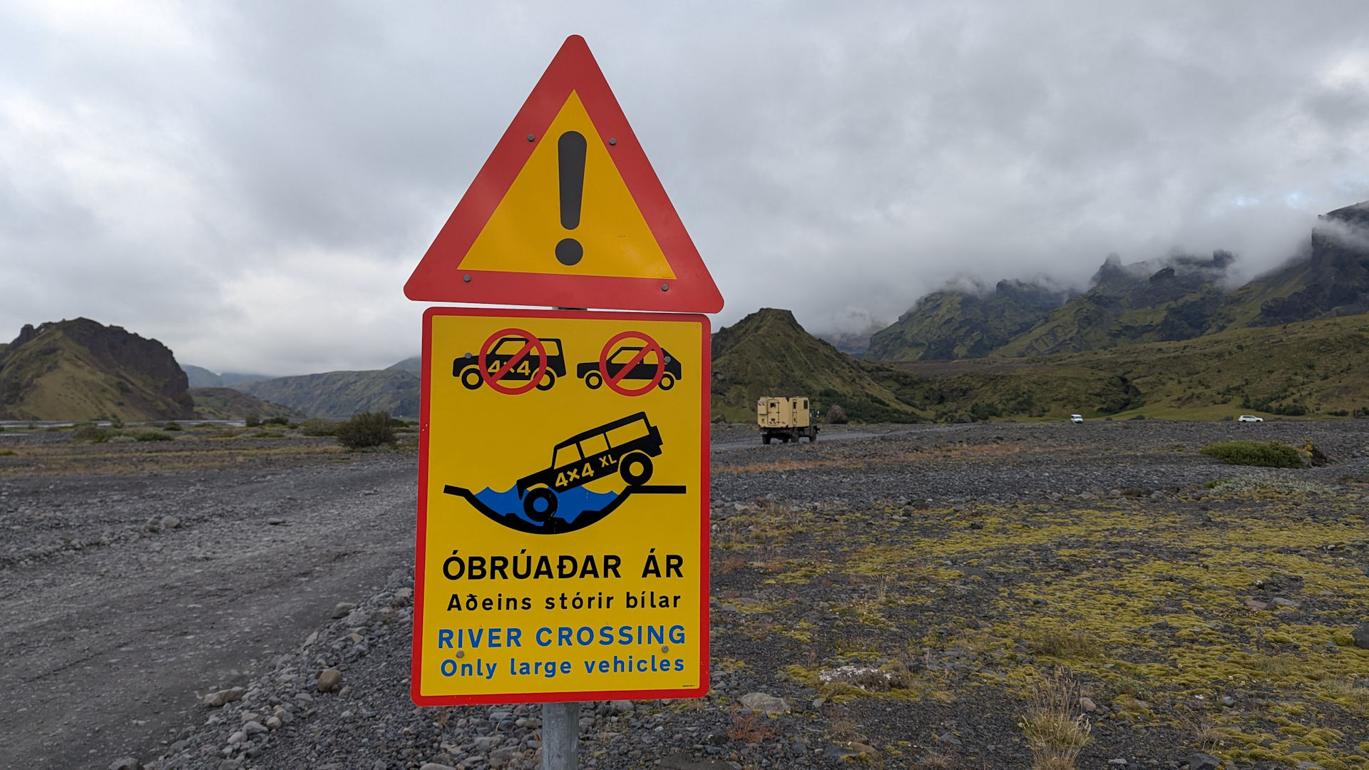 Hinweisschild in Island dass eine sehr tiefe Furt bevor steht. Auf dem Bild befährt ein 4x4 Auto mit dem Zusatz XL eine Furt. Kleine Autos nur mit 4x4 sind durchgestrichen. 