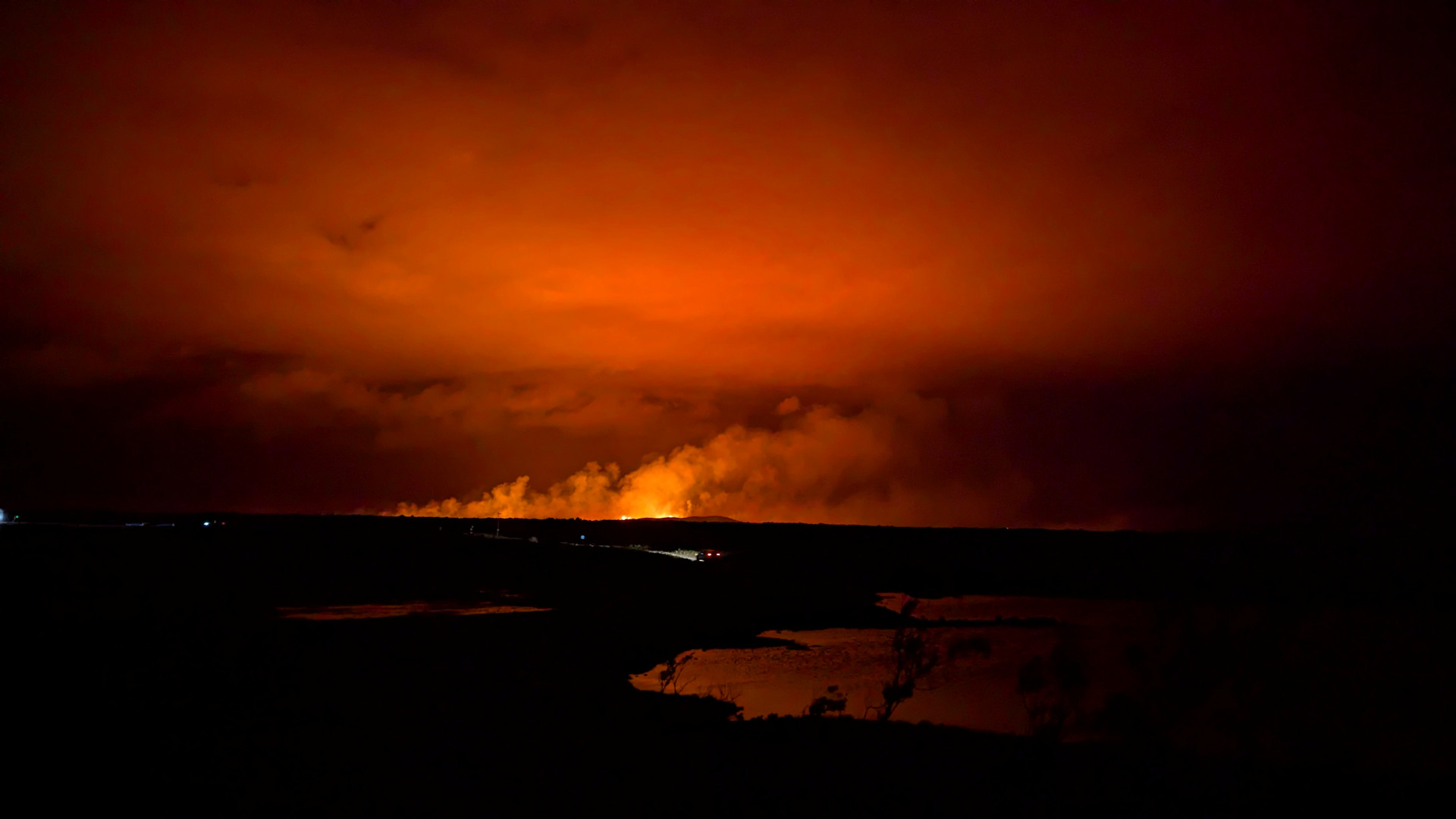 Vulkanausbruch in Grindavik mit rot leuchtenden Himmel und See