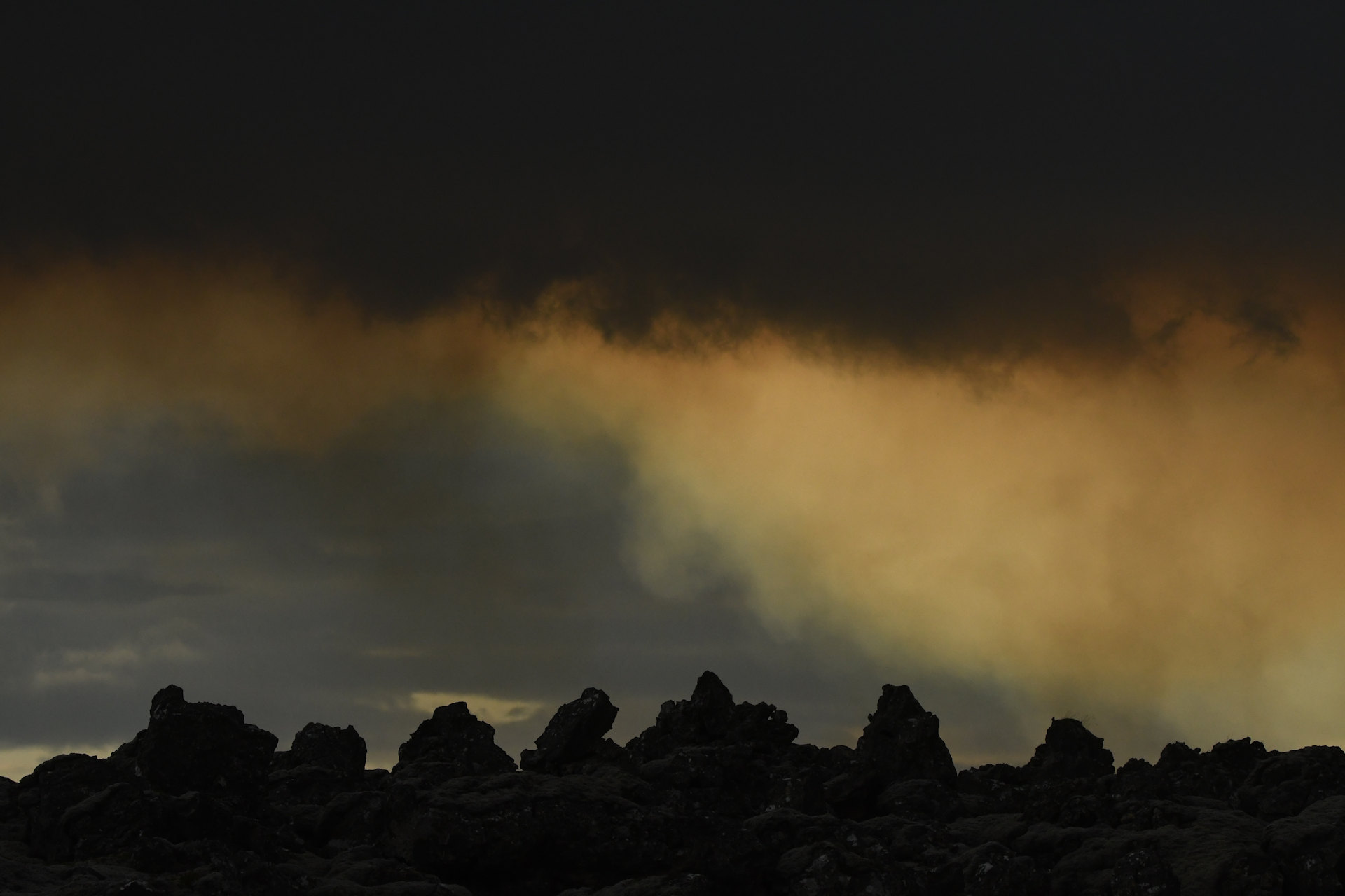 Dunkle Wolken und rissiges Vulkangestein