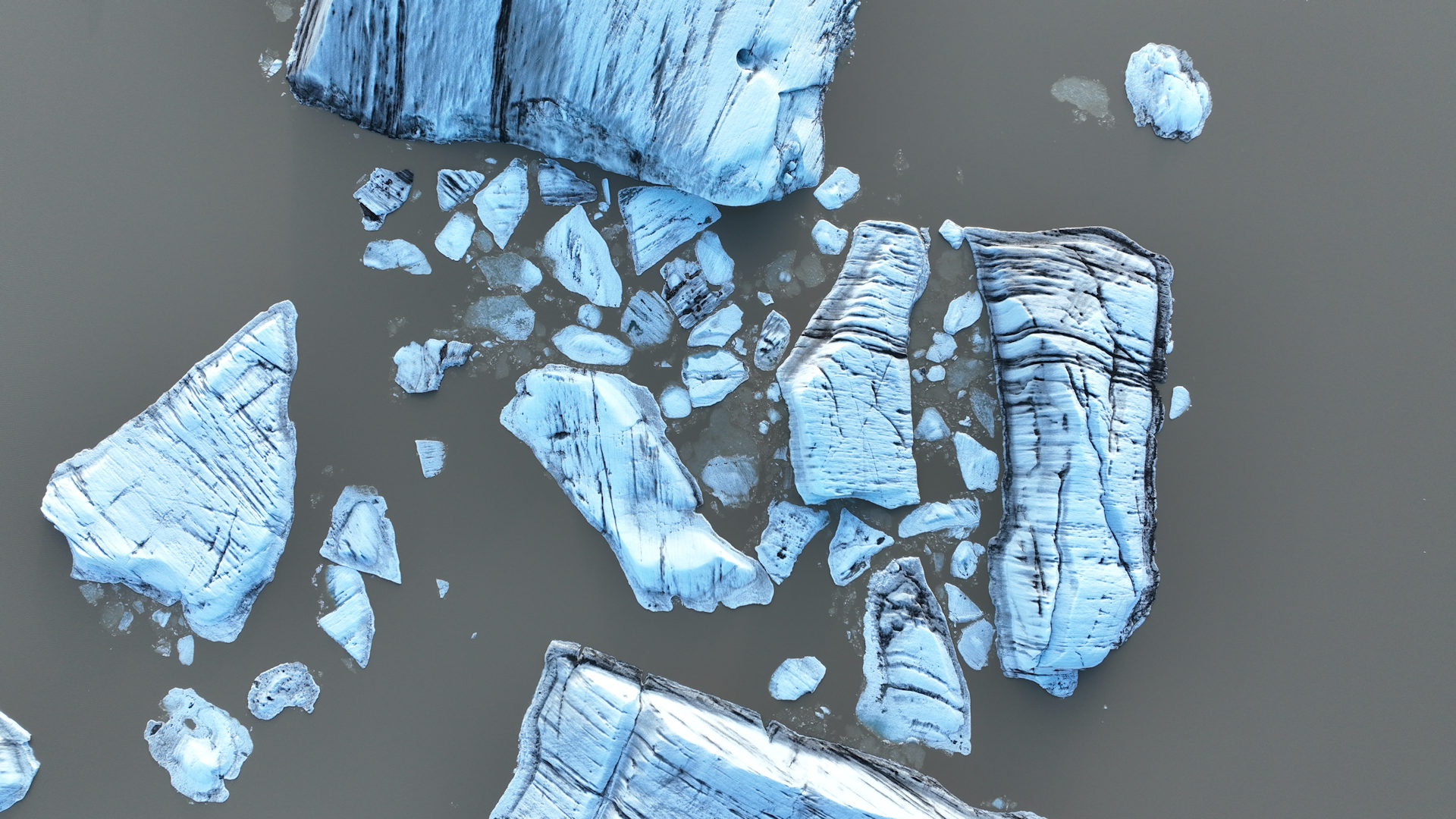 Luftbild blau leuchtender Eisblöcke in einem Gletscher See