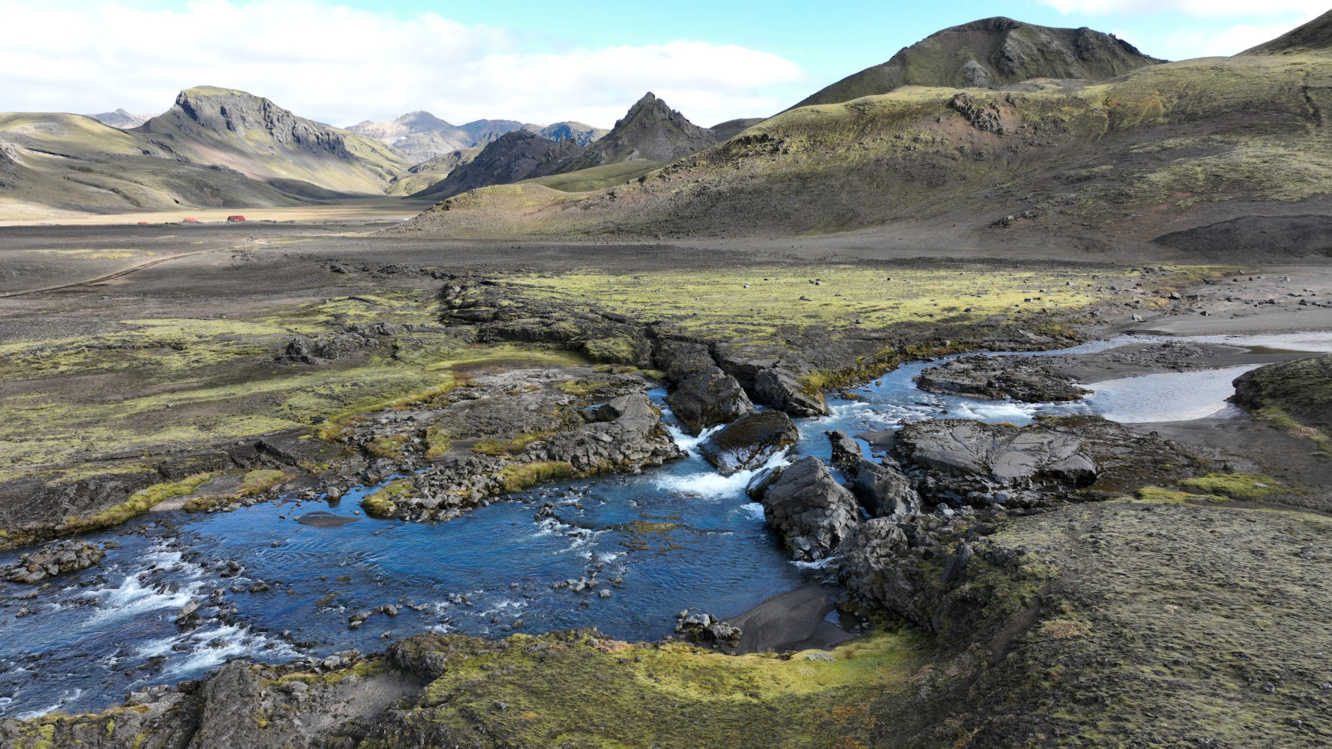 Blauer Bach fliesst durch ein Moos bewachsenes Lavafeld