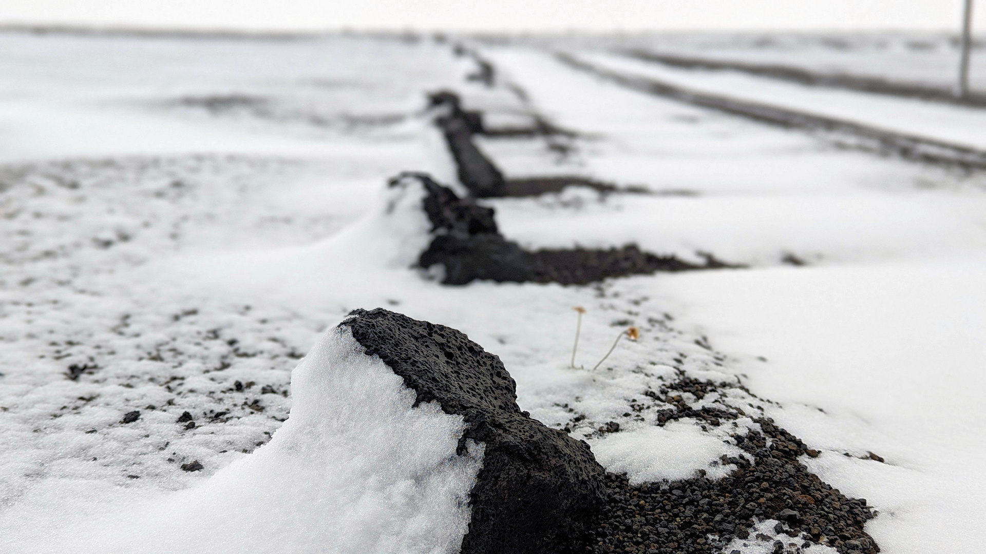 Poröser Lava Stein mit leichter Schneeverwehung am Rande einer Piste in Island