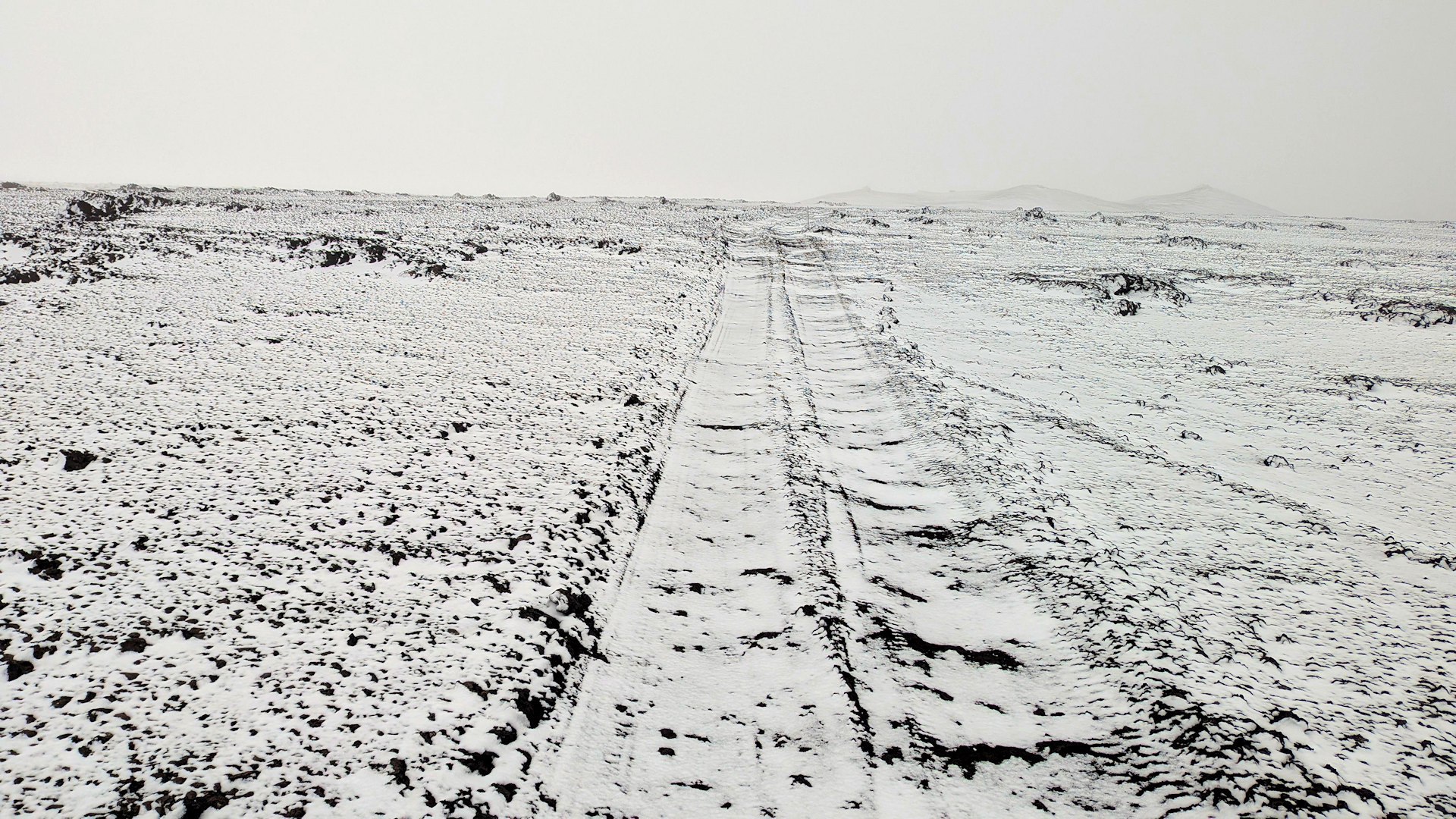 Verschneite Piste in Island mit martentem schwarz weissen Kontrast zwischen Schnee und schwarzer Lava