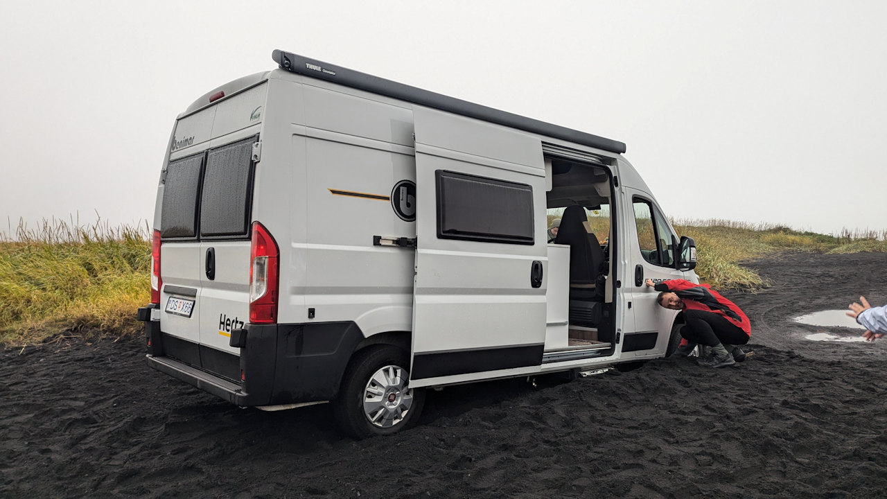 Kastenwagen der sich im schwarzen Sand festgefahren hat