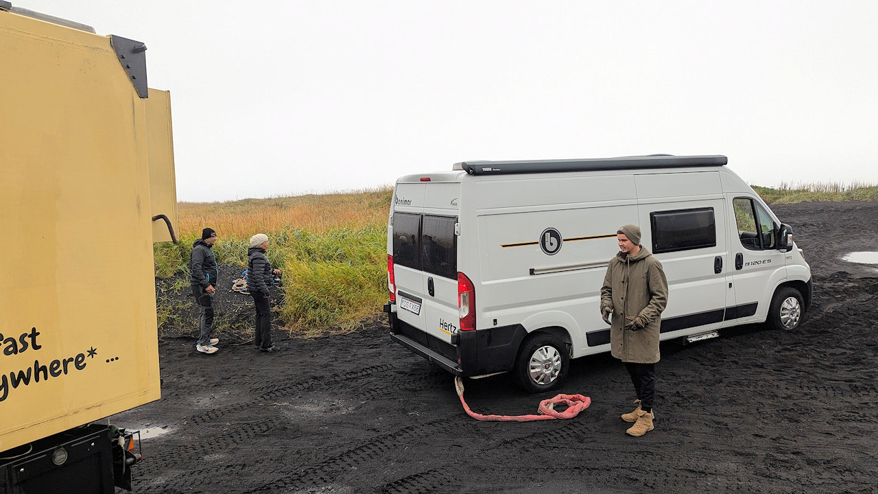 Kastenwagen der mit einem roten Bergungs Seil aus dem Sand bezogen wurde. 