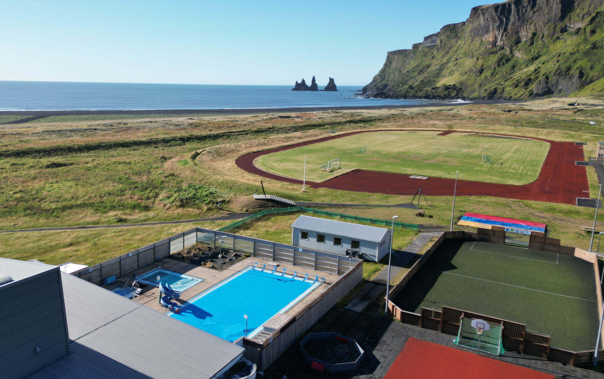 Luftbild Vik Island mit Bick auf das Schwimmbad und den schwarzen Strand