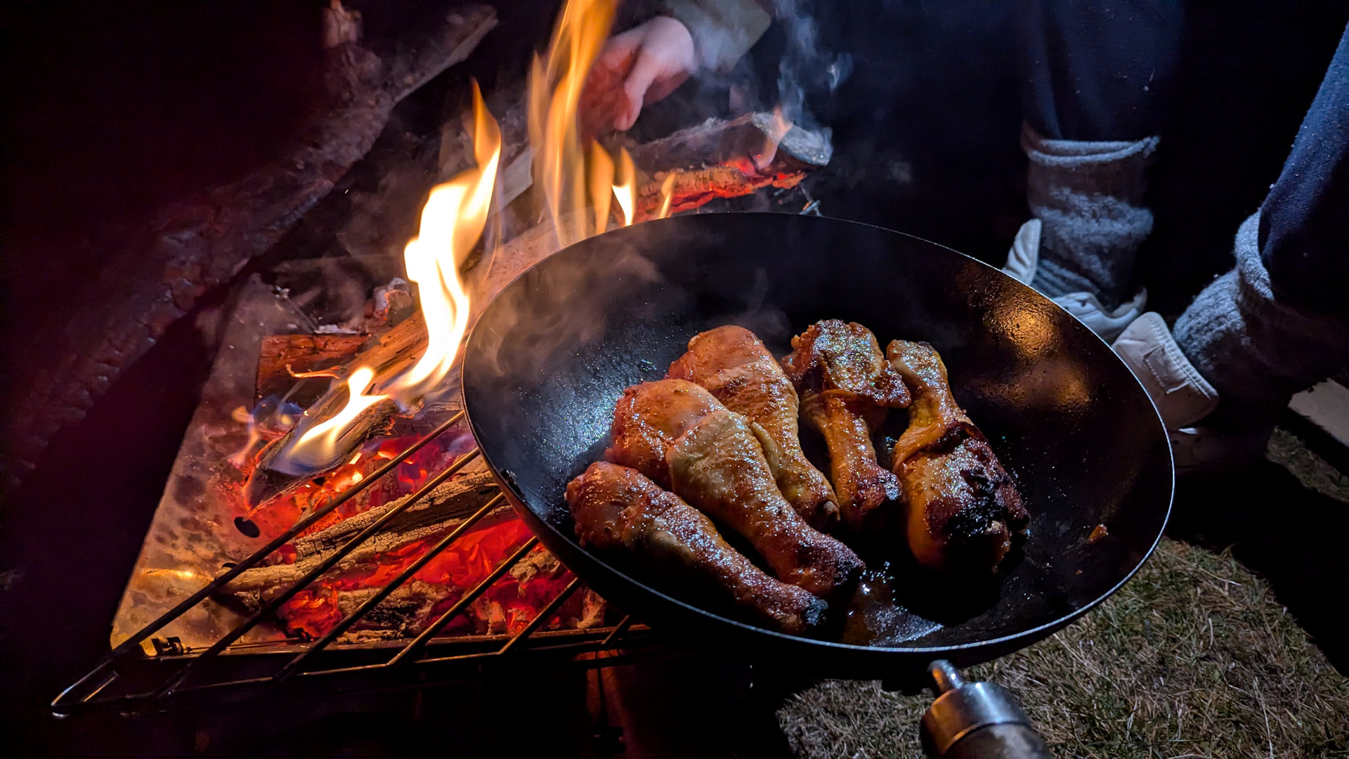 Knusprige Hähnchenschenkel in einer Pfanne an einem Lagerfeuer