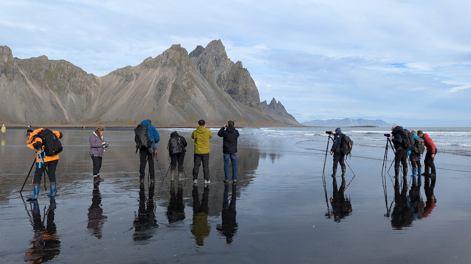 Eine Reihe Fotografen in Island vor dem Motiv Vesturhorn am überfluteten Strand