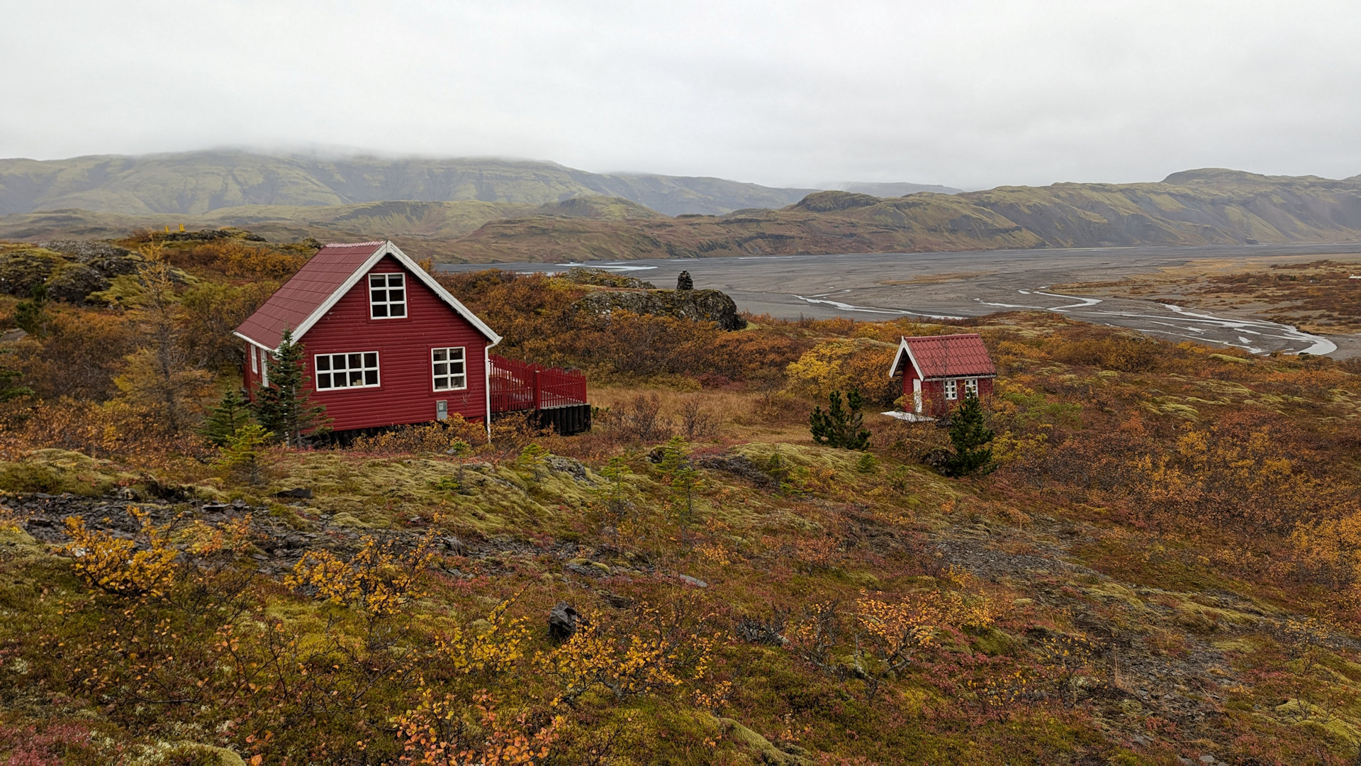 Zwei rote Ferienhäuser in Island Stafafell, umgeben von rot brauner Herbstlandschaft