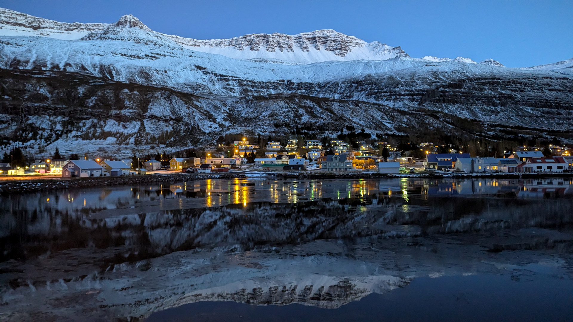 Seydisfjördur Nachts mit im Wasser spiegelnder Strassen und Häuser Beleuchtung