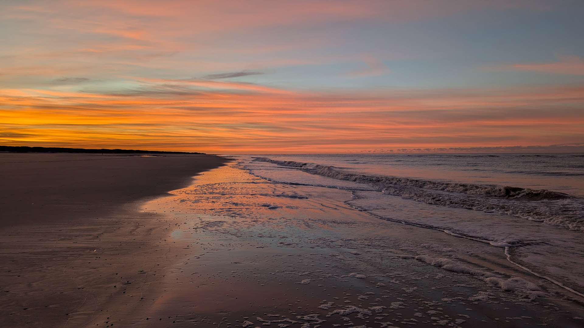 Sonnenuntergang mit rotem Himmel am Strand von Juist mit rot eingefärbten Wellen